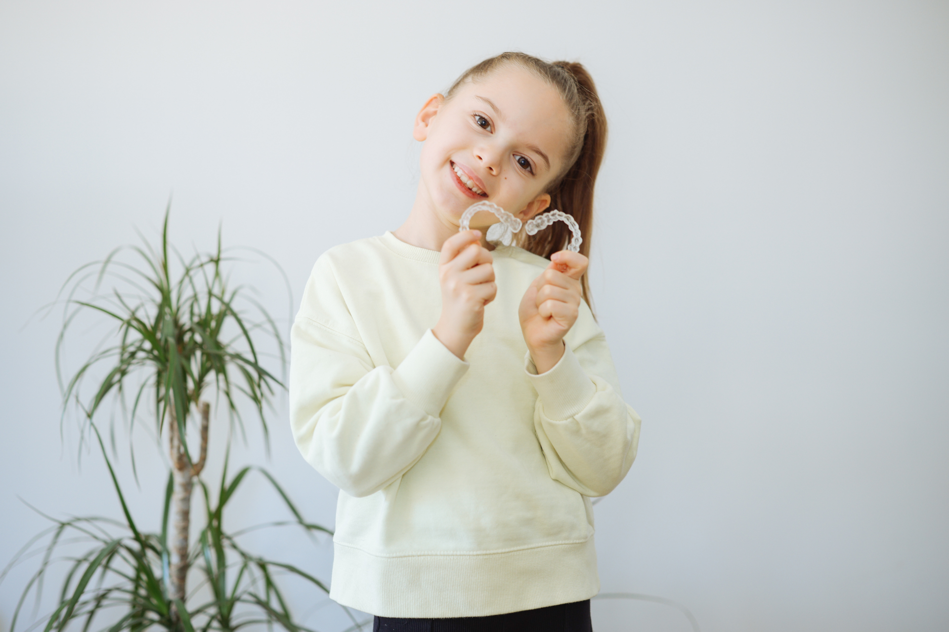 Child holding clear aligners for Phase 1 orthodontic evaluation in Cold Lake AB