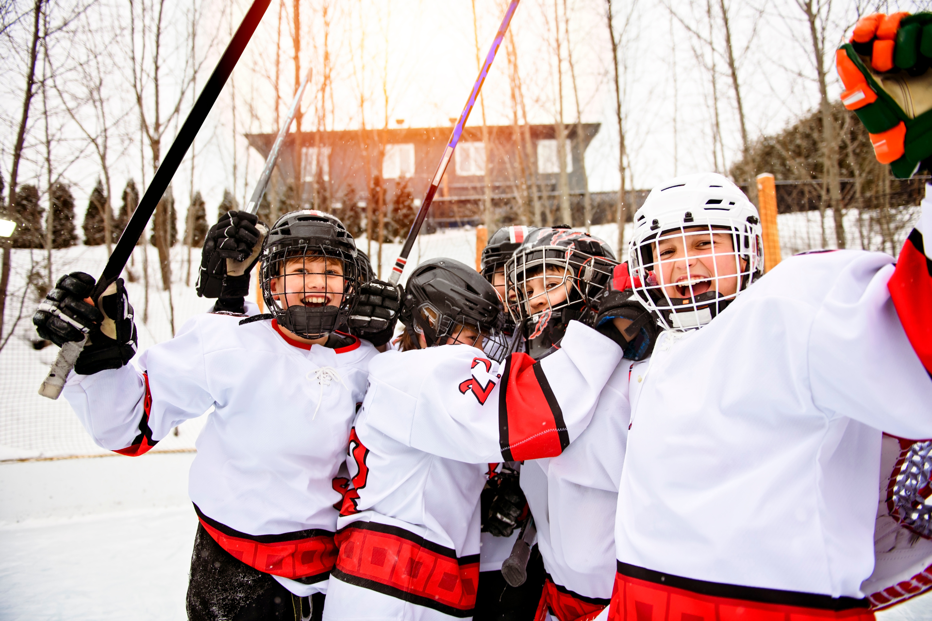 Group of young hockey players celebrating together on an outdoor ice rink