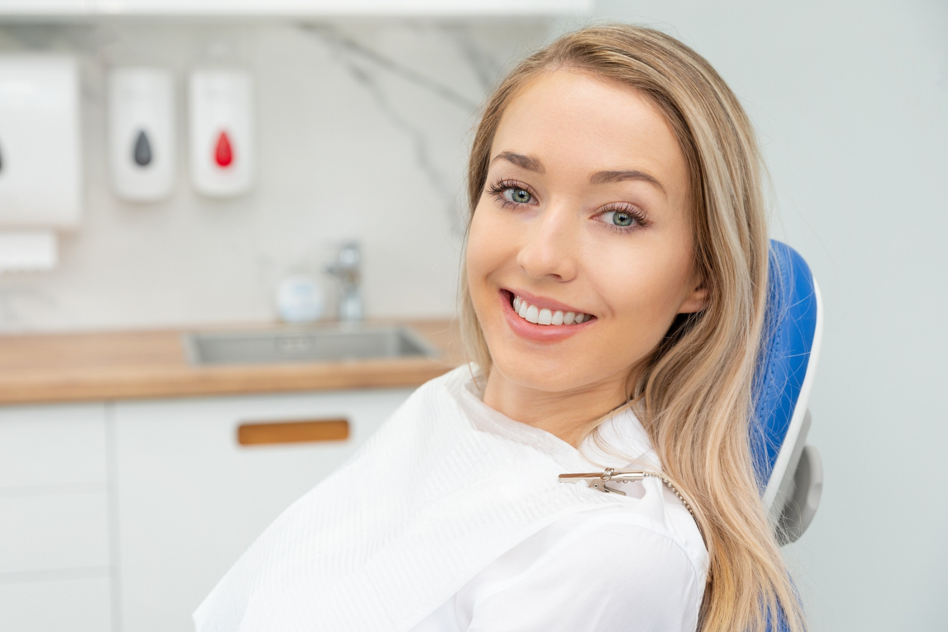 A cheerful blonde patient wearing a dental bib, ready for her orthodontic appointment.